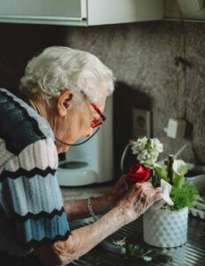Caregiver helps an older adult prepare breakfast in a bright, tidy home kitchen.