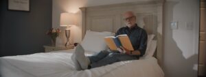 Older adult sitting comfortably in a living room with supportive handrails and bright natural light.